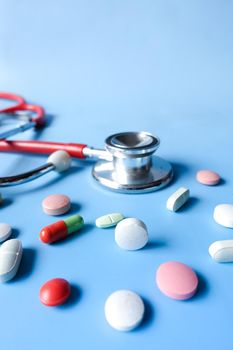colorful medical pills and stethoscope on blue background .