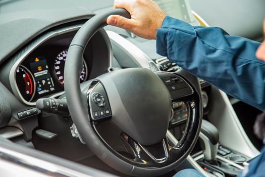 male hand on the steering wheel of a modern car. multifunction steering wheel and driver's panel. no face