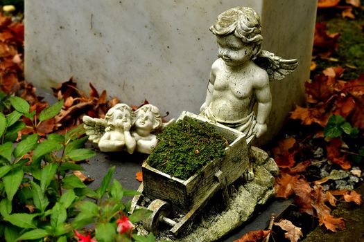 sweet angel figures on a grave in autumn with fallen leaves