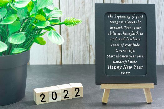Motivational and inspirational quote on black paper with potted plant and wooden block