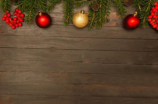 Christmas background.Two red christmas balls,one golden ball, red berries, fir cone and fir tree branches on wooden background.