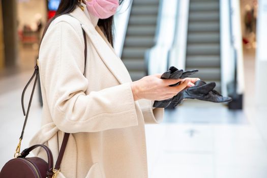 middle-aged woman takes off her gloves in the mall on escalator background. faceless