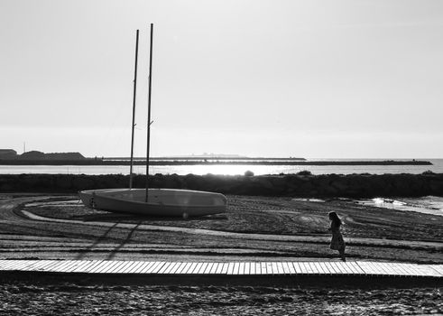 Santa Pola, Alicante, Spain- October 19, 2021: Beautiful sailboats on the shore and child running on Levante beach in Santa Pola, Alicante, Spain