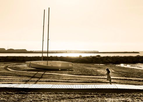 Santa Pola, Alicante, Spain- October 19, 2021: Beautiful sailboats on the shore and child running on Levante beach in Santa Pola, Alicante, Spain