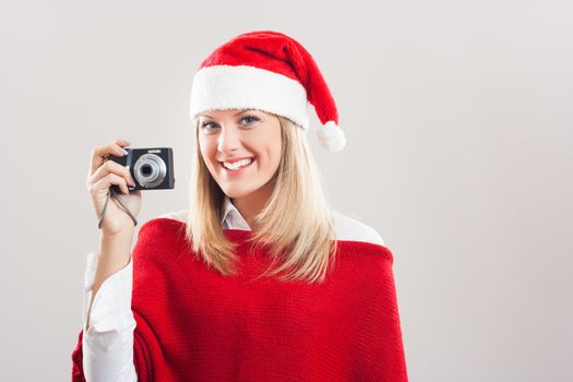 Beautiful young woman with Santa hat holding camera.