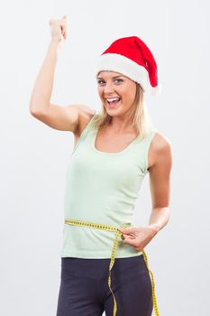 Portrait of happy woman with Santa hat measuring her waist.