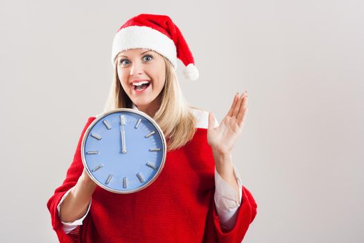 Portrait of beautiful happy woman with Santa hat holding clock.