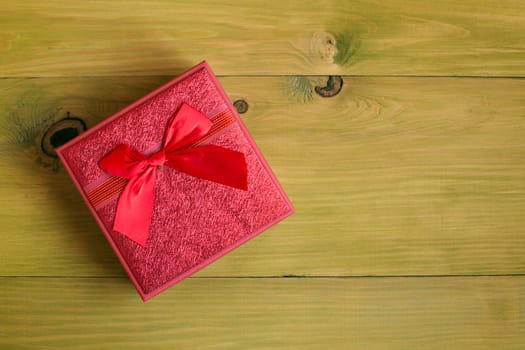 Image of gift in beautiful red box on wooden table.
