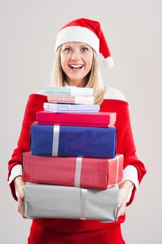 Happy woman with Santa hat holding bunch of gifts.