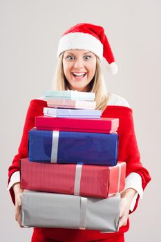 Happy woman with Santa hat holding bunch of gifts.