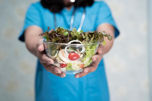 Nutritionist doctor holding various healthy fresh vegetables for patient.