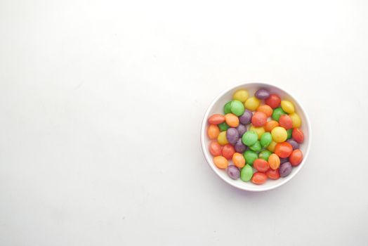 multi-colored sweet candies in a bowl on white background .