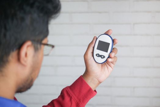 rear view of man's hand holding a glucose meter .