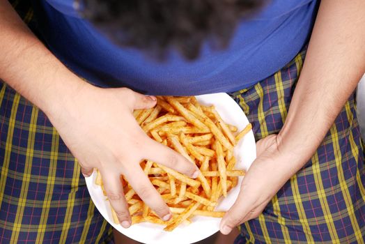 top view of a fat man hand pick french fries .