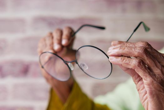 Close up of senior women hand holding old eyeglass.