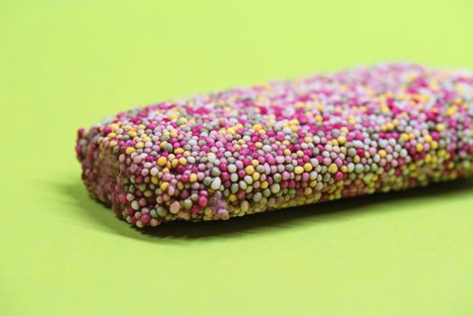 Ice cream on stick with colorful sprinkles over green background