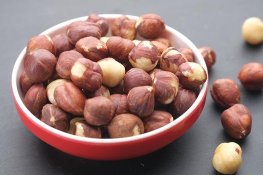 hazelnuts in a container on black background