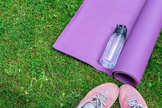Sneakers, water bottle and a purple fitness mat. Sport concept, top view. Sport concept