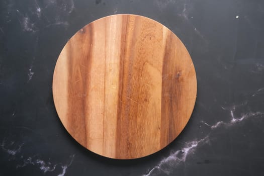 wooden chopping board on black background top down.