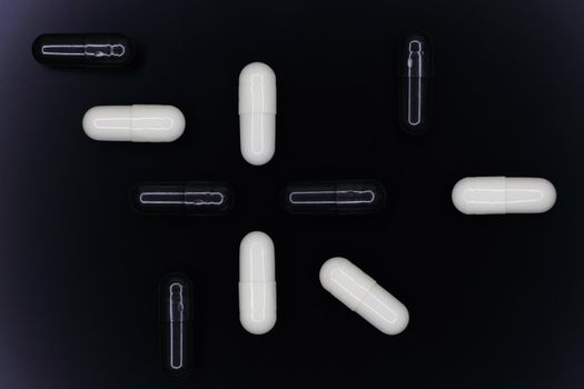 Black and white gel pill capsules abstract layout on smooth black surface