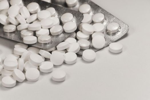 White prescription medication pills and packaging trays close-up abstract on white