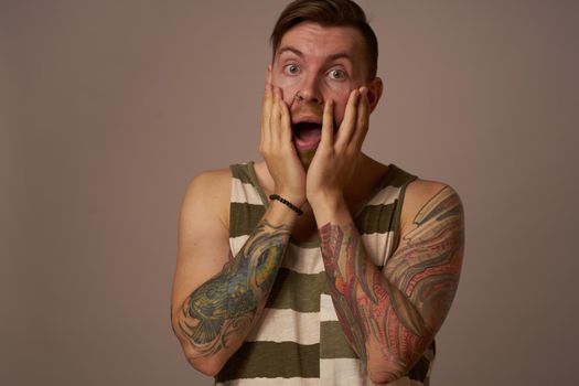 handsome man with tattoos on his arms fashionable hairstyle emotions. High quality photo