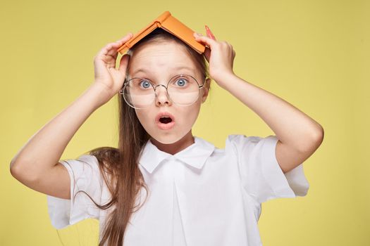 schoolgirl with textbook in hands learning childhood yellow background. High quality photo