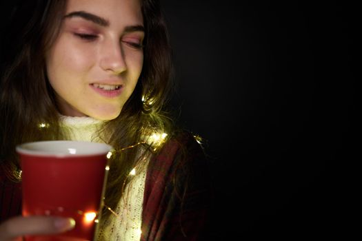 woman with a cup of drink garland decoration holiday comfort. High quality photo