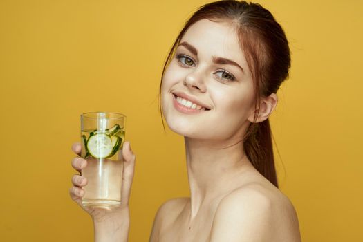 woman with cucumber drink vitamins body care yellow background. High quality photo