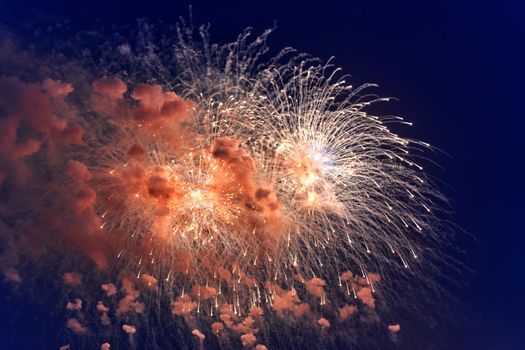 Blurred multicolored fireworks lights against the dark night sky. Festive fireworks. Light defocus