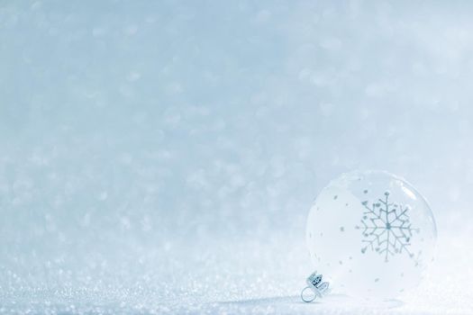 Beautiful transparent Christmas ball with snowflake over festive glitter background