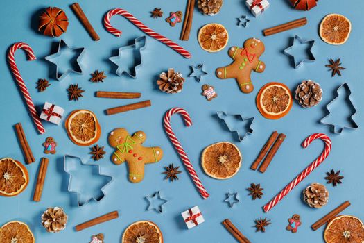 Christmas food background. Gingerbread cookies, candy canes spices and decorations on blue