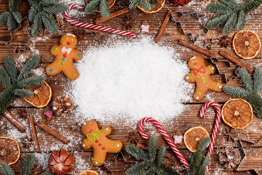 Christmas food frame. Gingerbread cookies, spices and decorations on wooden background with white copy space on white snow