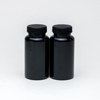 Black plastic pill jars on a white background. Isolated