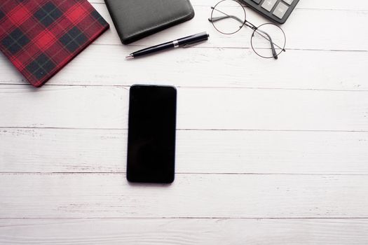 top view of smart phone and notepad on table .