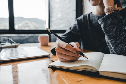 Close up of student girl hand writing on notebook on a desk at home