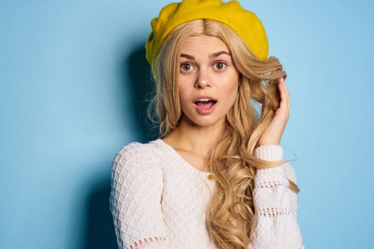 woman in yellow hat posing glamor blue background. High quality photo