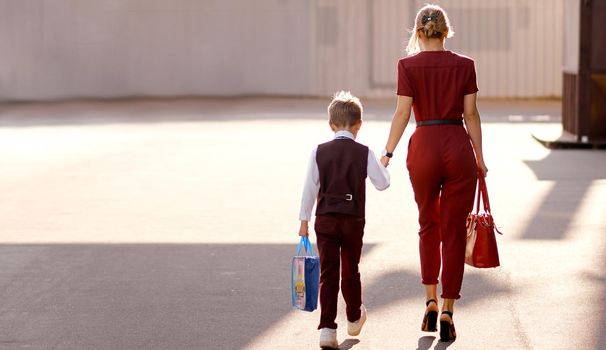 Mother with son on the way to new study year with bags. High quality photo