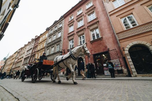 WARSAW, POLAND - Mar, 2018 Tourists ride in a carriage with horses in the historic part of the city of Warsaw 1