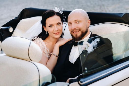 Elegant wedding couple In the courtyard of the castle in a retro car.