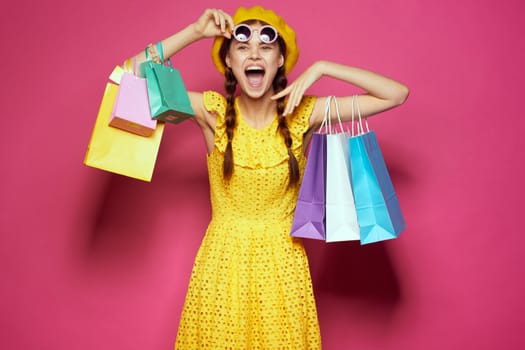 cheerful woman in a yellow hat Shopaholic fashion style pink background. High quality photo