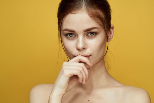 pretty woman naked shoulders and posing clear skin yellow background. High quality photo