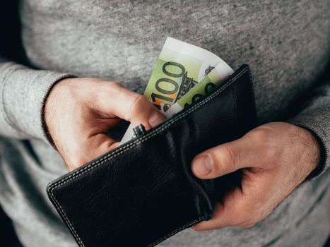 Hands take out Euro from wallet. Closeup on a man's hands as he is getting a banknote out of his wallet