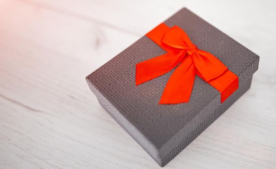 Gift box present isolated with clipping path with red bow satin on pine wood background. High quality photo