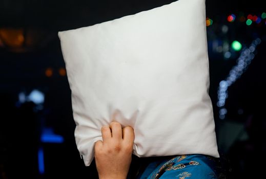 back view of man hiding face with pillow in club party. High quality photo