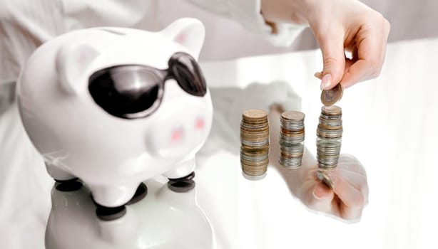 Girl collects coins in stacks next to pig piggy bank . High quality photo