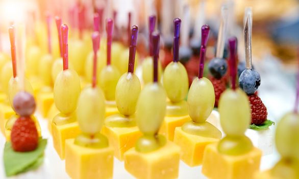 Catering. On the table cheese, grapes, blueberries, blackberry on skewers . High quality photo