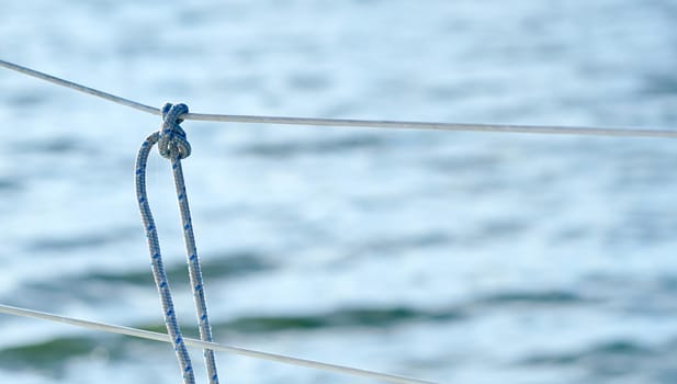 Knot on the fence of the yacht board against the background of the ocean sea water. High quality photo