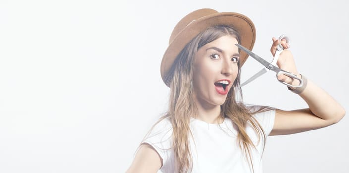 A woman wearing a hat looking through scissors hight quality