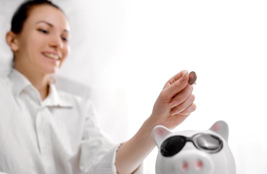 Happy woman tops up her savings in pig piggy bank. High quality photo